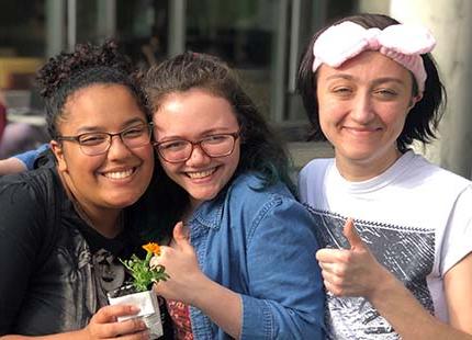 three students holding a flower